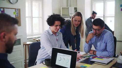 Group of Young Businesspeople with Laptop Working Together in a Modern Office
