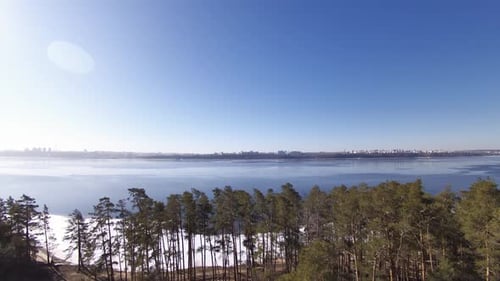 Cityscape beyond a wide river. Large and wide river near forest and city. Spring.