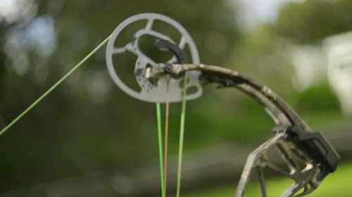 A shot of the top Cam of a compound bow as the bow is drawn and fired.