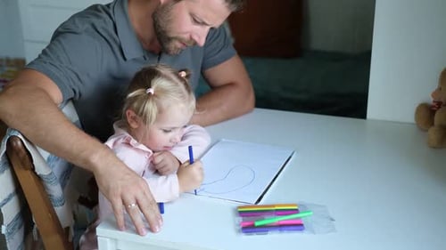 Young Child Drawing at Table with Adult