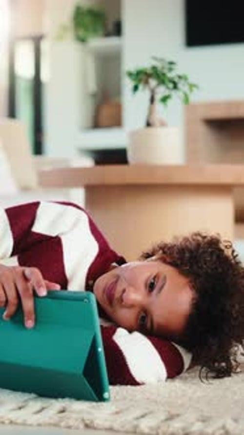 Child, reading and relax with tablet in house, elearning or skill development with assignment