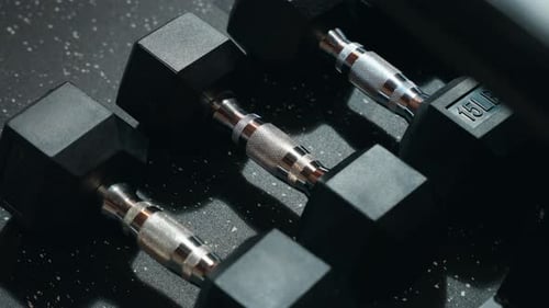 A 4K Row of Basic Black and Knurled Silver Metal and Rubber Weighted Exercise Dumbbells on a Synthet