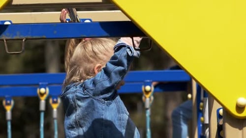 Girl with a blue jacket playing on playground in city park