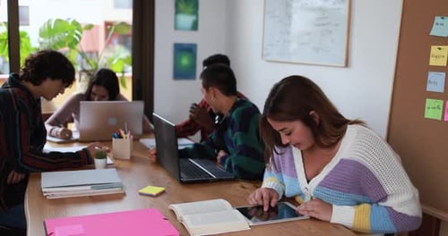 Multiracial Students Using Laptop and Digital Tablet While Studying Together Inside Library