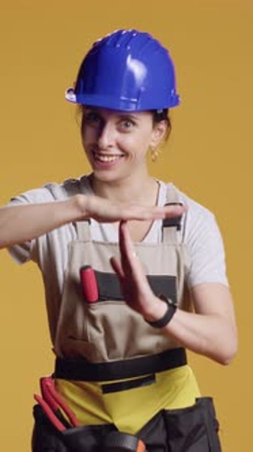 Vertical Video Portrait of Woman Contractor Showing t Shape Sign in Studio