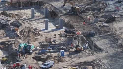Sitio de construcción con maquinaria y trabajadores en la zona del puente sur de Riga