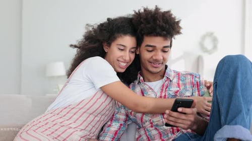 Loving Couple Using Mobile Phone on Sofa