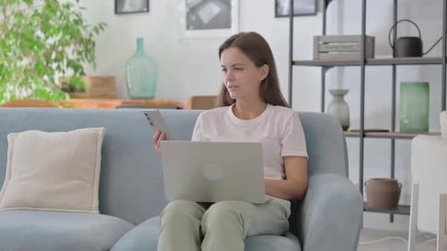 Woman Using Laptop and Phone on Couch