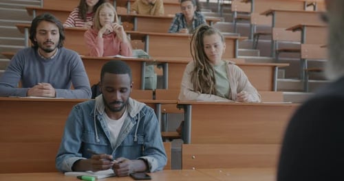 Cheerful African American Man Asking Question Talking to Teacher Sitting in University Hall with