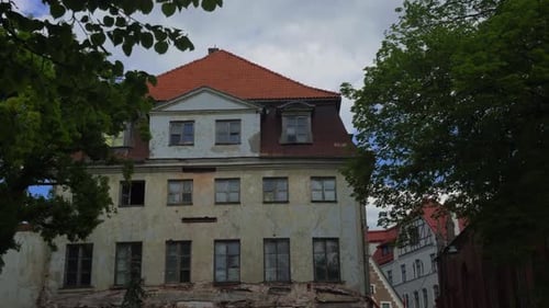 Beautiful Old Building Featuring a Striking Red Roof Surrounded By Lush Greenery Beneath a Cloudy