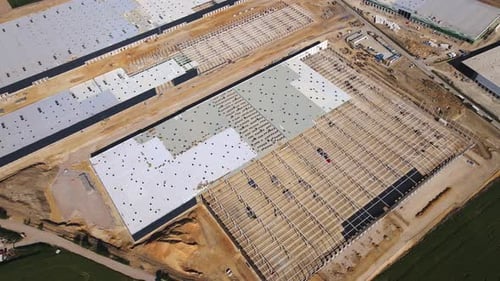 Construction site with steel frame structure of warehouse building, aerial view