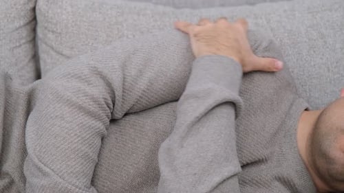 Man Massaging Shoulder While Laying on Couch