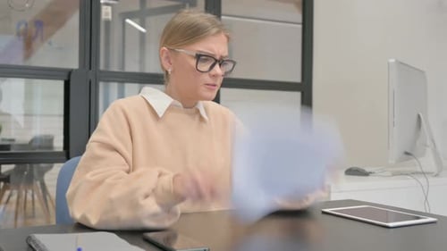 Woman Reviews Documents with Frustration in the Office