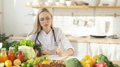 Una guapa nutricionista habla sobre los beneficios de una nutrición adecuada sobre los alimentos saludables en su cocina