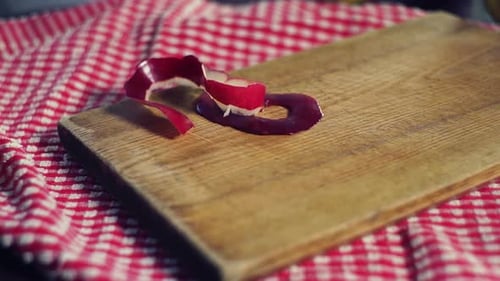 Apple peel falling onto the wooden cutting board