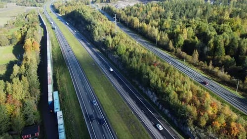 Aerial view of highway vehicle traffic through northern autumn forest