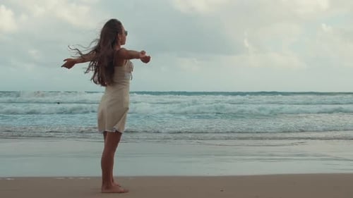 Woman Standing on Beach with Arms Outstretched