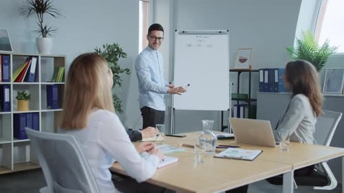 Beliebter Business-Coach steht in der Nähe des Zeichenbretts Attraktive Frau, die spricht, Arbeiter hören jung zu