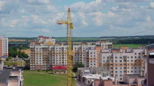 Arbeitskran am Bausatz des Gebäudes. Sonniger Tag. Feld im Hintergrund