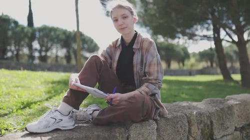 Young Woman Writing Outdoors in a Park