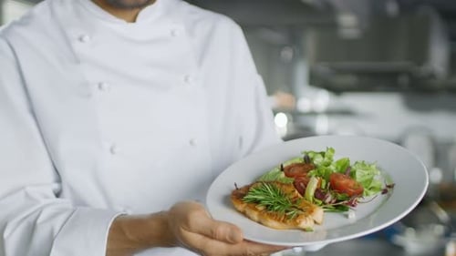 Famous Male Chef Presents His Special Dish. He Stands in a Big Restaurant Kitchen.