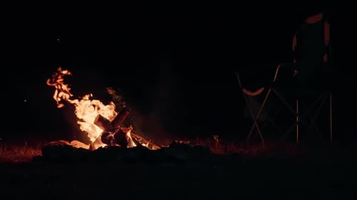 Burning Campfire Outdoors at Night Beside Camping Chair