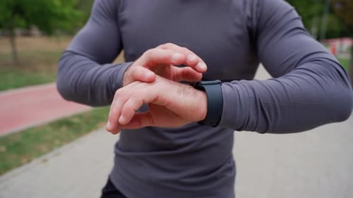 Man Uses Smartwatch in Urban Setting