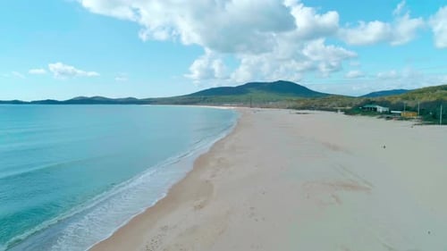Aerial View of Sandy Beach and Turquoise Ocean Ocean Waves Reaching Shore on a Cloudy Day Camera