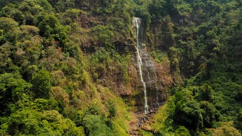 Tall tropical waterfall Diamante cascading down lush green cliff in Costa Rica