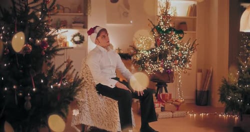 Worried Man Sitting on Chair at Illuminated Home During Christmas