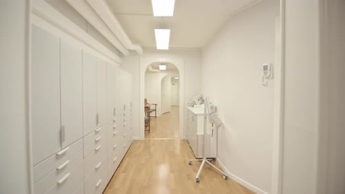 Patient POV walking down medical centre corridor into bright dentist's office