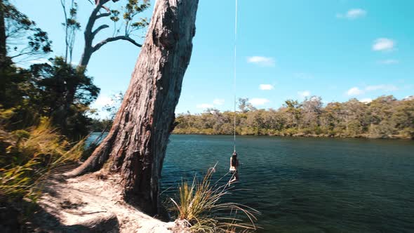 Rope swing jump girl summertime. Girl swings on rope swing into ...