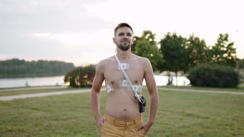 Un hombre con sensores de monitoreo de ECG Holter en el cuerpo camina al aire libre al aire libre