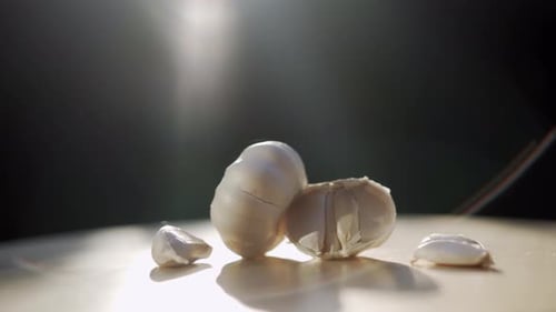 Garlic on wooden table top in bright rays of sunlight moving shot left to right.