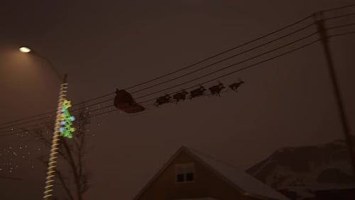 Der Weihnachtsmann fliegt mit Rentieren und Schlitten über Häusern in einer magischen Weihnachtsnacht