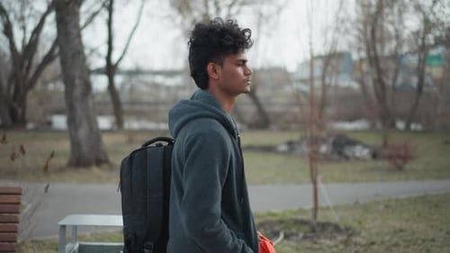 Indian Man Standing Outdoors in Park During Early Spring Wearing Gray Hoodie