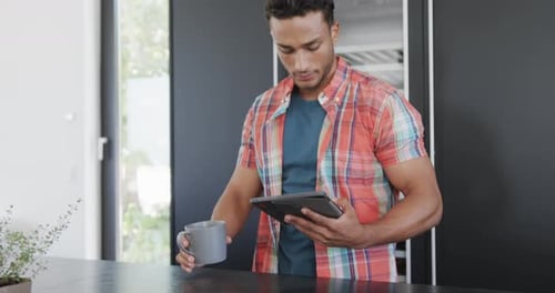 Young Adult Man Using Tablet in Kitchen