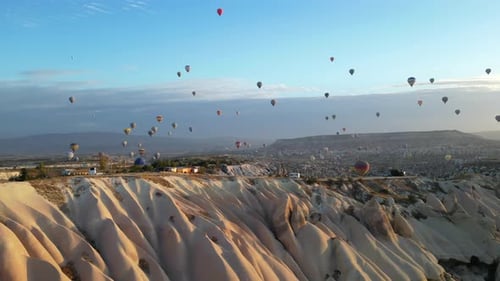 Balloons float over surreal valley landscape