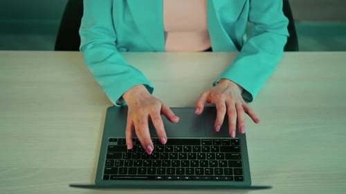 Woman Types on Laptop at Office Workplace