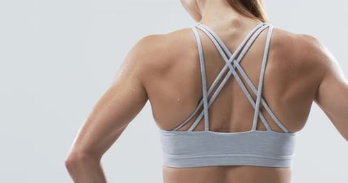 Close-up of a young Caucasian woman athlete's back, showcasing sportswear on a white background