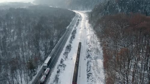 Aerial Shot of Train Moving Along Snowy Railway in Forest in the Winter Season.
