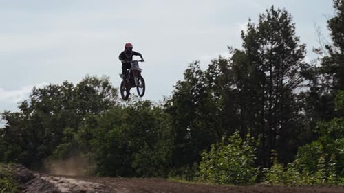 Slow motion Dirt Bike Rider gains air time. Big jump over the hill. Professional race driver on dirt