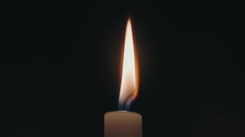 Brennende Kerzenflamme vor dunklem Hintergrund