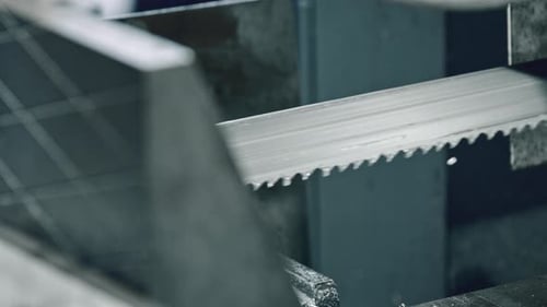 Precision cutting with metal bandsaw in industrial workshop