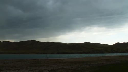 Captivating time-lapse Summer rainstorm over the fast-flowing river with majestic mountains, creatin
