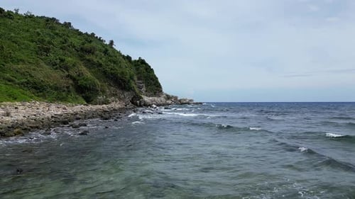 Tieffliegende Luft über Wellen, die an der felsigen Küste einer tropischen Insel krachen