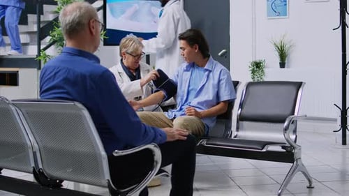 Doctor Checks Young Adult's Blood Pressure in Clinic