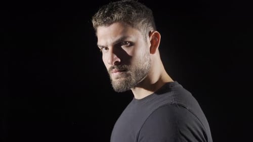 Man Stares Intensely Into Camera on Dark Background