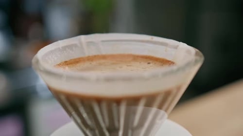 making filter coffee by pouring hot water on a layer of ground coffee on the filter coffee flowing