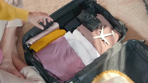 Woman packing clothes in luggage for new journey